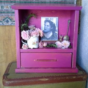 a small magenta personal altar, called a zendohous, in honor of a family ancestor, with photo, flowers and other memorabilia