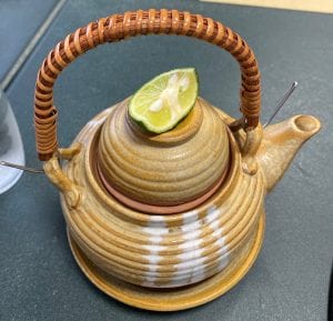a small teapot holds a savory and delicate mushroom broth, a single serving, to be garnished wth a wedge of citrus