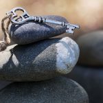 a decorative metal key sits on tumbled stones