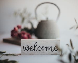 a friendly "welcome" sign, along with flowers and a tea pot